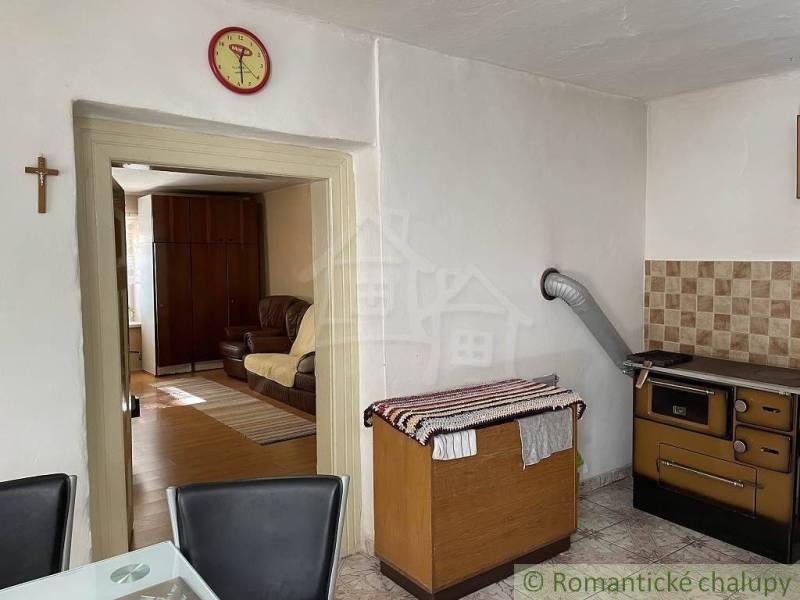 Interior of a family house with a kitchen, an old stove, and a view into the living room.