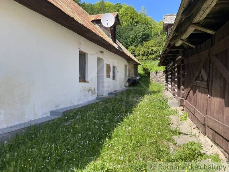 Traditional family house with wooden structure, garden, and greenery in the countryside.