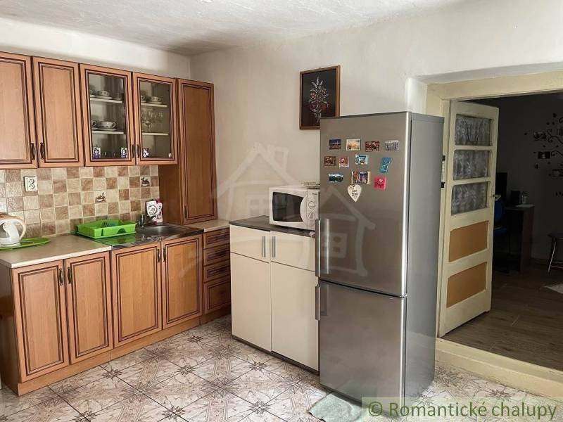 A kitchen in a family house with wooden cabinets, a sink, and a stainless steel refrigerator.