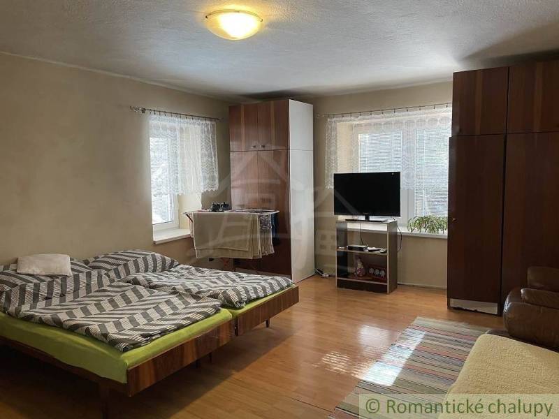 Interior of a room with a TV, bed, sofa, and cabinets in a family house.