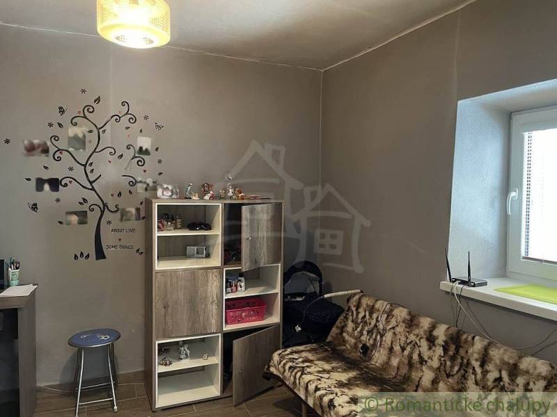 A room in a family house: a comfortable sofa, furniture, wall decoration, and a lamp.
