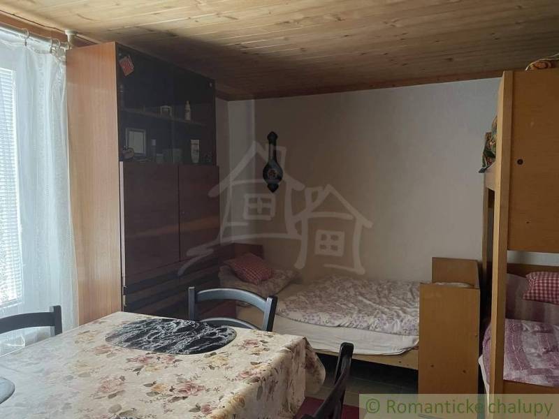 Room in a cabin with a wooden ceiling, bunk bed, and dining table.