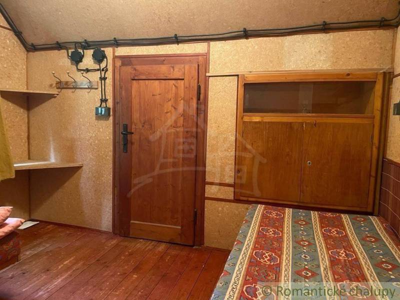A wooden cabin with patterned bedding, wooden furniture, and walls create a rustic atmosphere.