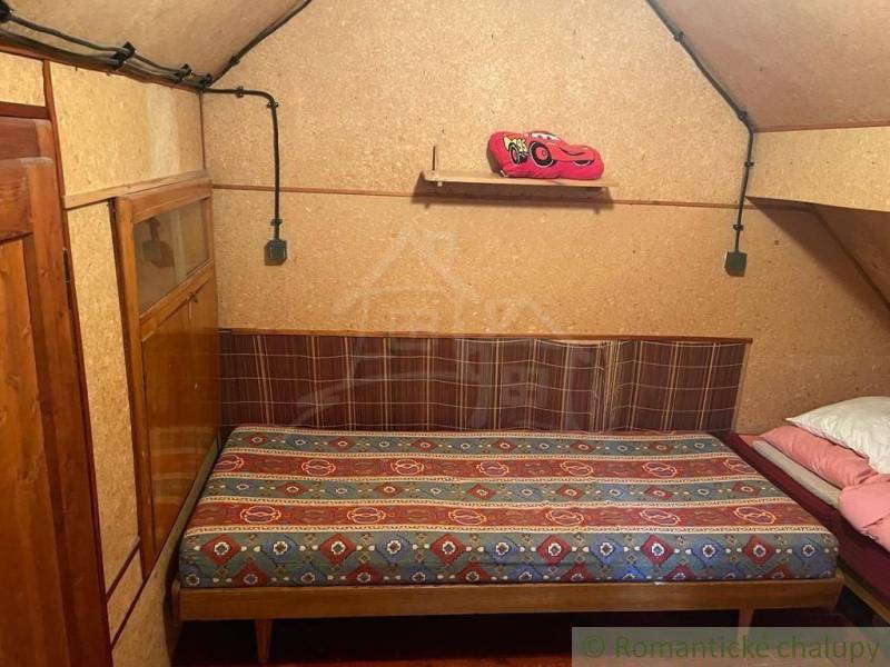 A simple room with a bed, wooden paneling, and a cabin atmosphere.