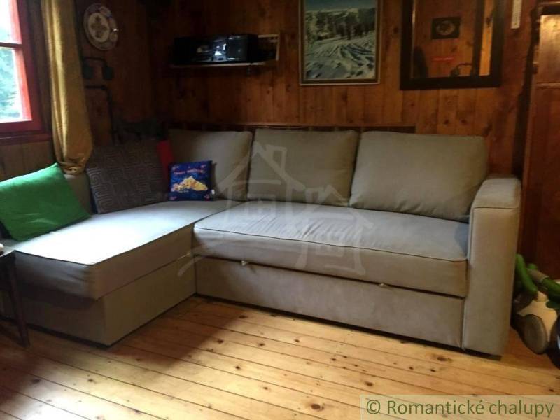 The image shows a cozy room in a cabin with wooden walls and a comfortable couch.