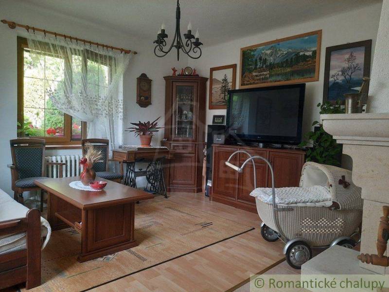 Living room with furniture, retro stroller, paintings, and a family house in a traditional style.