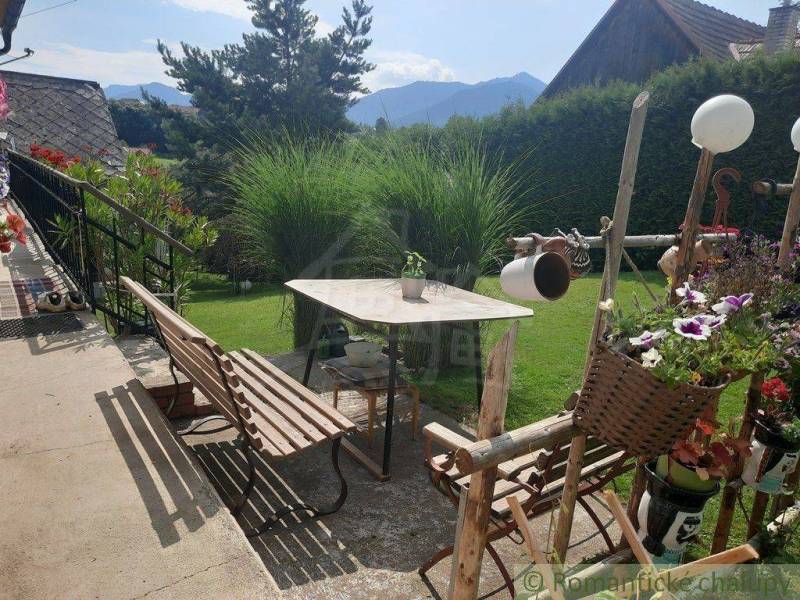 Garden and family house, benches, table, flowers, mountains in the background, lawn.