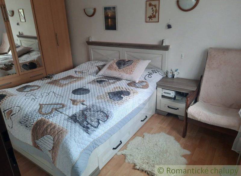 A comfortable bedroom containing a double bed, a wardrobe, and an armchair. Accessories adorn a cozy family home.