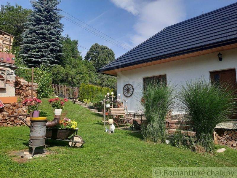 A family house in a garden with flowers, wood, and a lawn. Romantic cottages in the countryside.