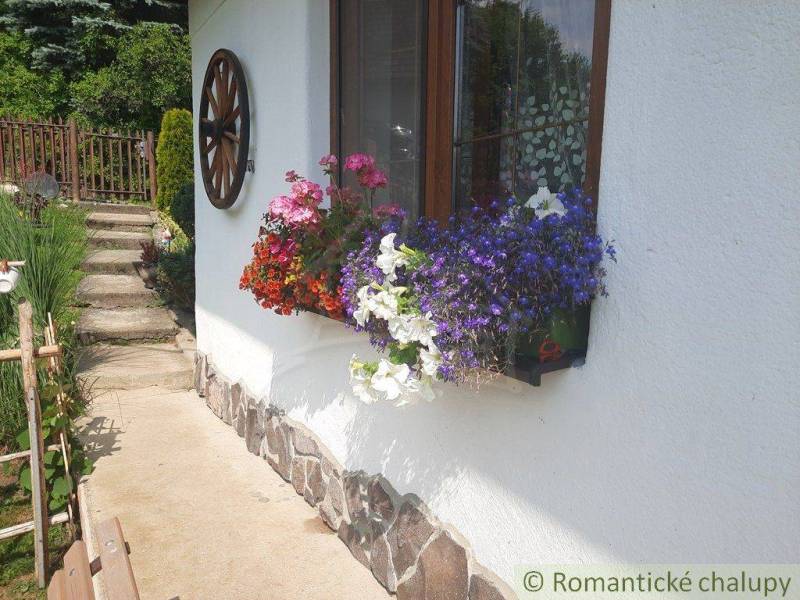 Flower decoration on the window of the house, next to the stairs and a wooden wheel on the walls.
