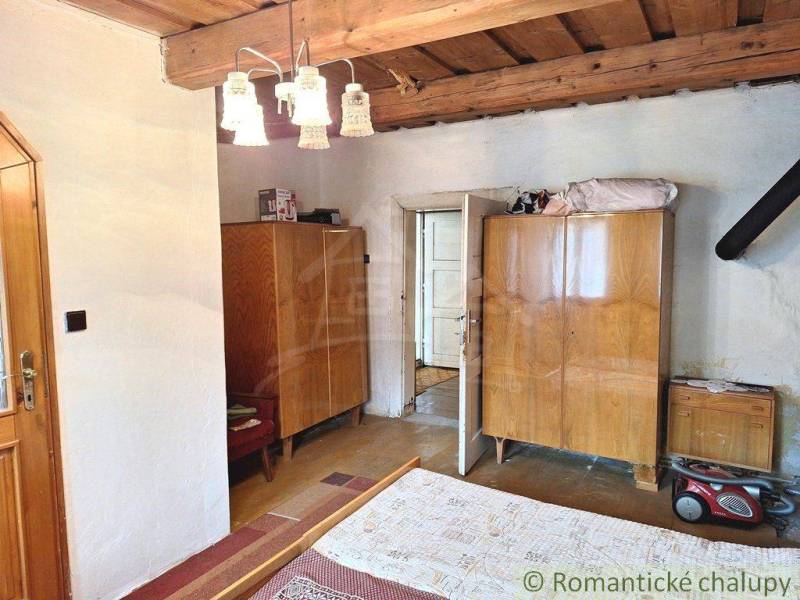 A room with a wooden ceiling, antique cabinets, and rustic doors in a family house.