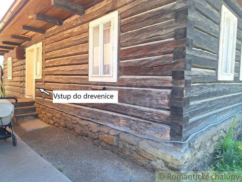 A log cabin with a stone foundation and a family house with steps leading to the entrance of the cottage.