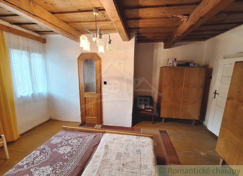 A cozy room with wooden beams and furniture in a family house is visible.