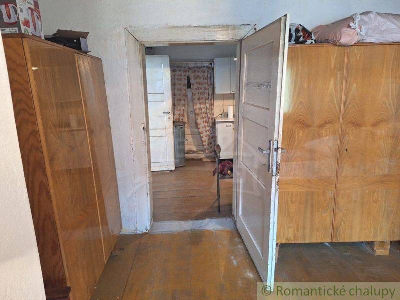 A hallway with wooden cabinets leads to the kitchen in a family house, through open doors.