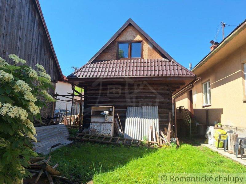 A rustic family house with a garden, wooden elements, and a large shrub for a peaceful atmosphere.