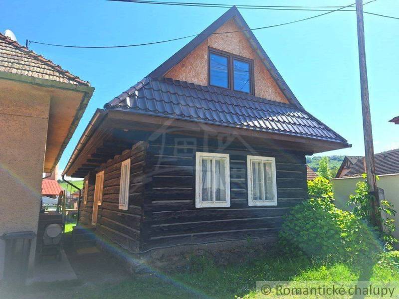 A traditional wooden house with windows and an attic in a sunny setting, a family home in the village.