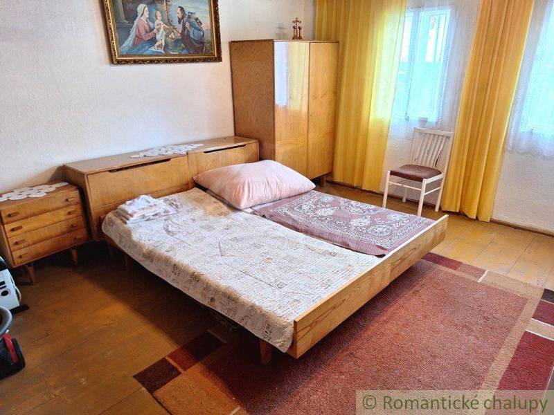 A bedroom in retro style with wooden furniture, a carpet, and a family house complements the cozy atmosphere.