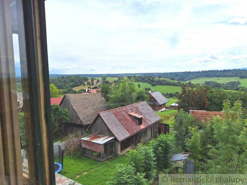 The image shows a view of a rural family house and green countryside.