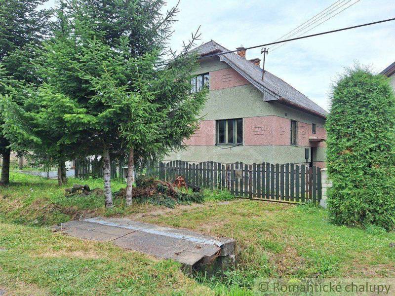 The picture shows a family house surrounded by trees and a fence.
