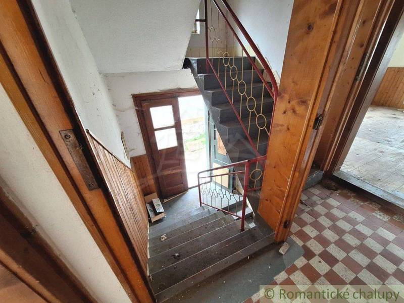 Staircase and entrance door in a family house with wooden paneling and tiles.