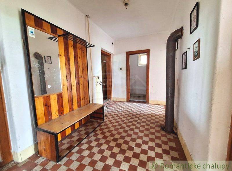 Entrance hall with a bench, mirror, tiles, and pictures in a family house.