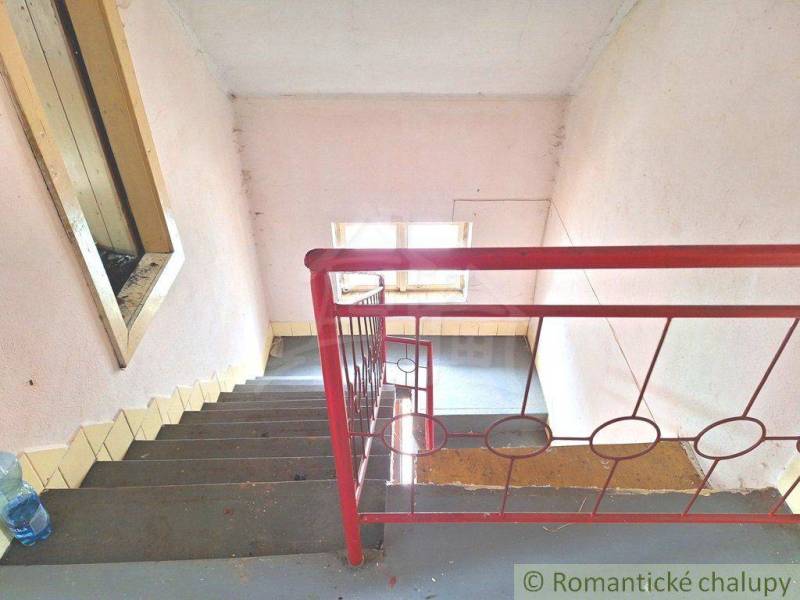 A staircase with a red railing in an older family house, with light coming through the window.