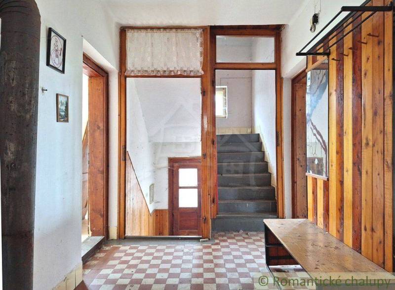 Entrance hallway in a family house with wooden paneling and a stone staircase.