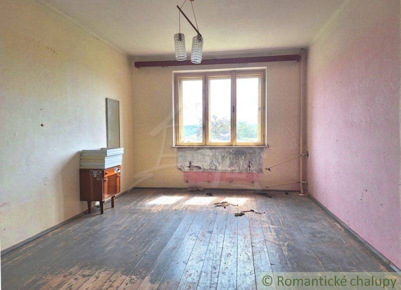 An abandoned family house with wooden floors, worn-out walls, an old chandelier, and an empty interior.