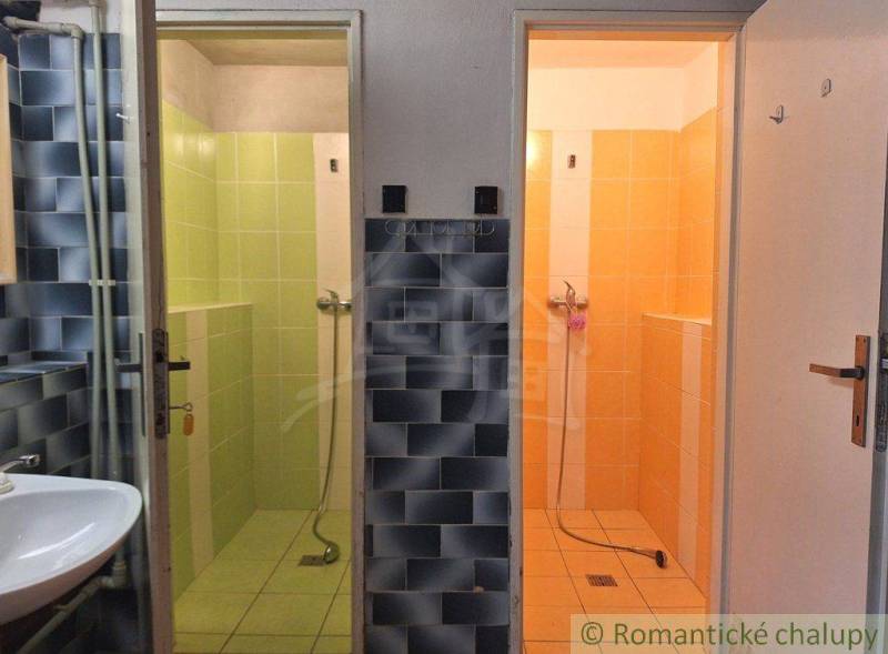 An interior with two shower cabins in colored tiles: green and orange. Commercial spaces.