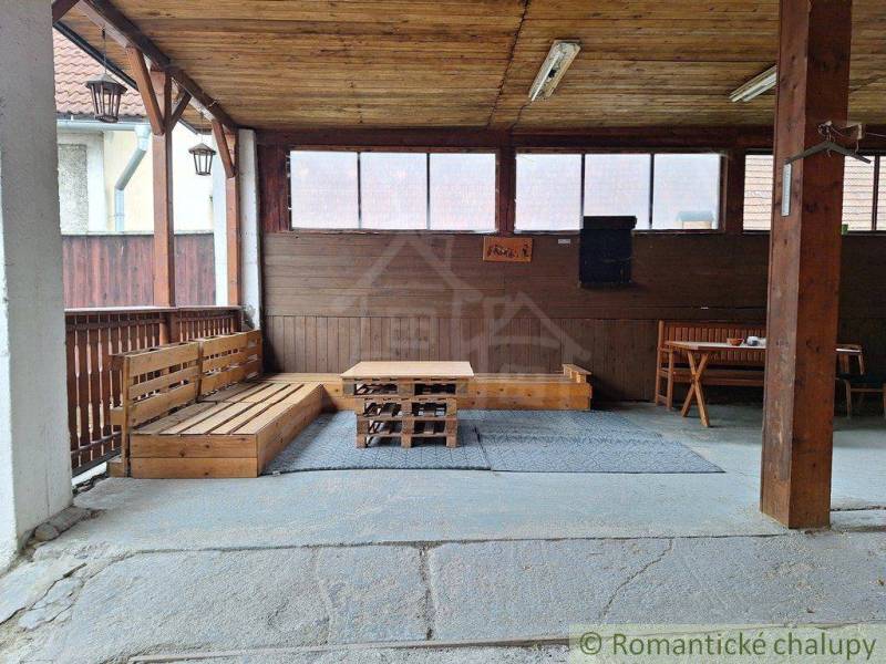 Wooden terrace with seating and a table in a family house, ideal for romantic cottages.