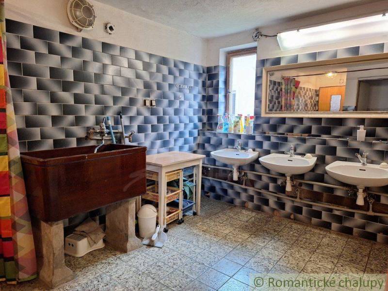 Rustic bathroom with sinks, wooden cabinet, and dark wall tiles.