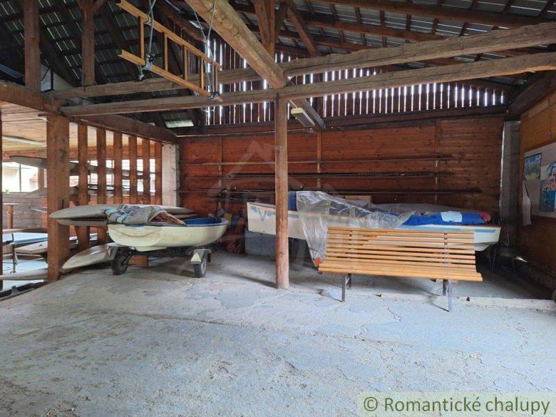 Wooden storage building with boats and a bench, suitable for vacationers and a family house.