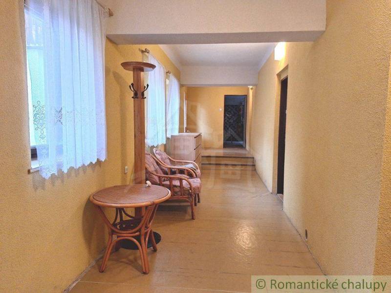 A hallway with yellow walls, rattan furniture, and curtains, ideal for commercial spaces.