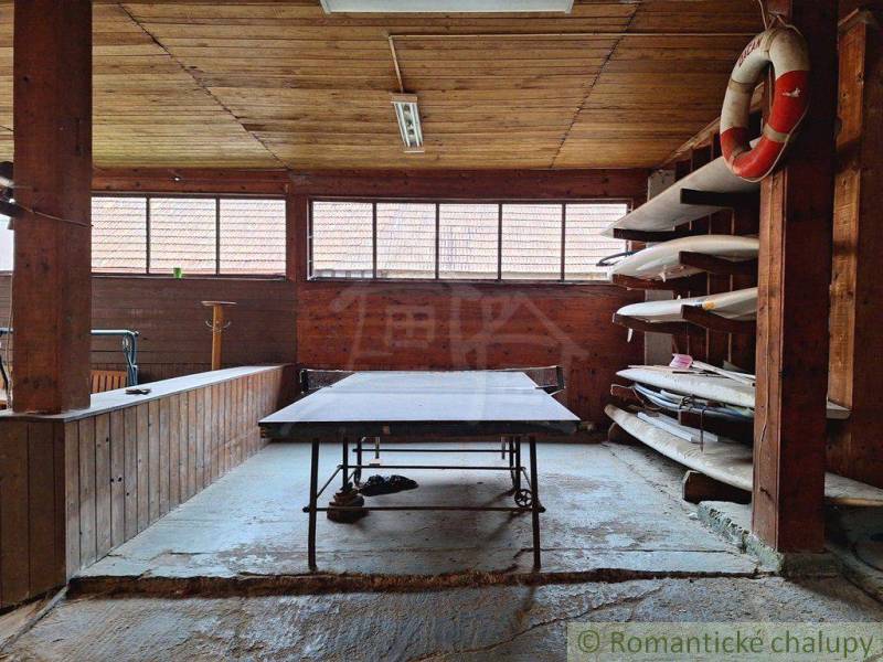 Ping pong table and shelves with kayaks in a wooden building suitable for a family house.