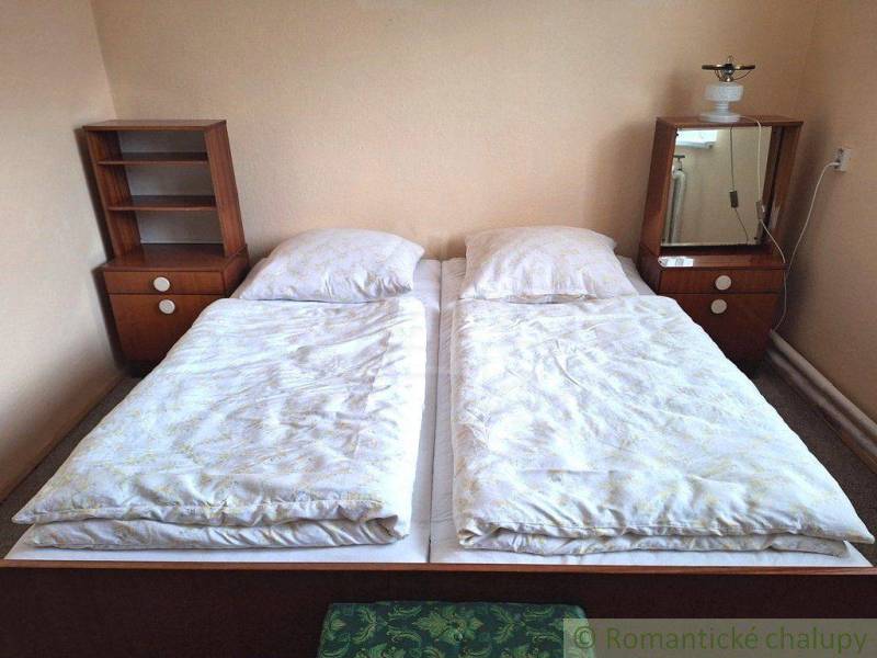 A bedroom with simple beds, nightstands, and a lamp, suitable for a family house.