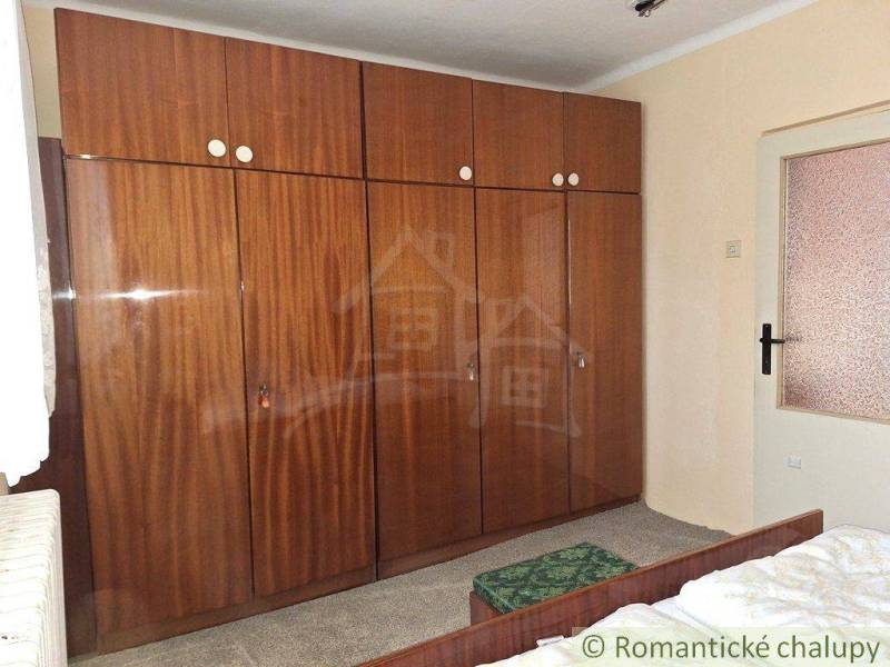 In the room, there is a large wooden wardrobe, a bed, and the interior doors of a family house.