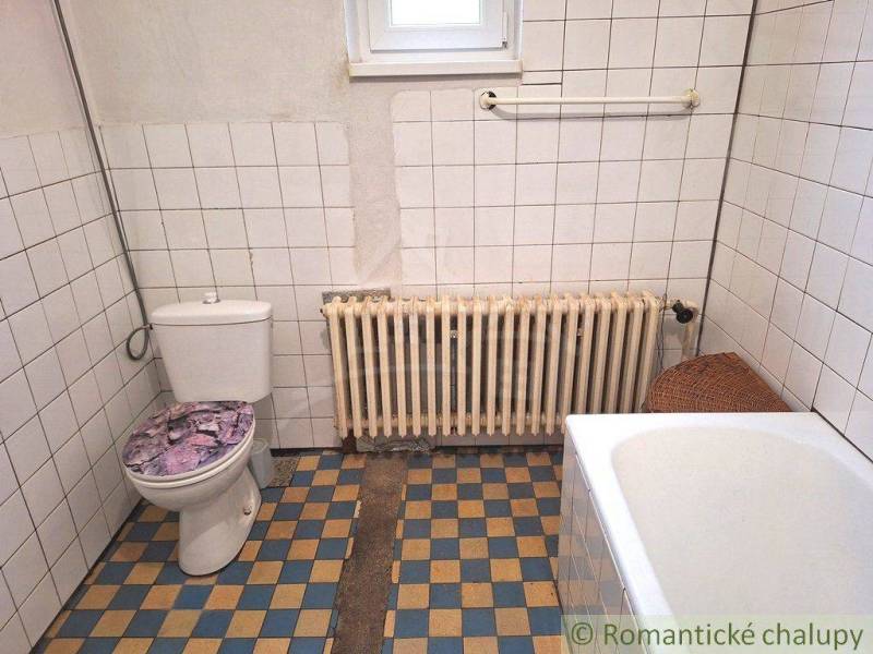 A family house bathroom with tiles and a radiator, showcasing a simple and clean design.