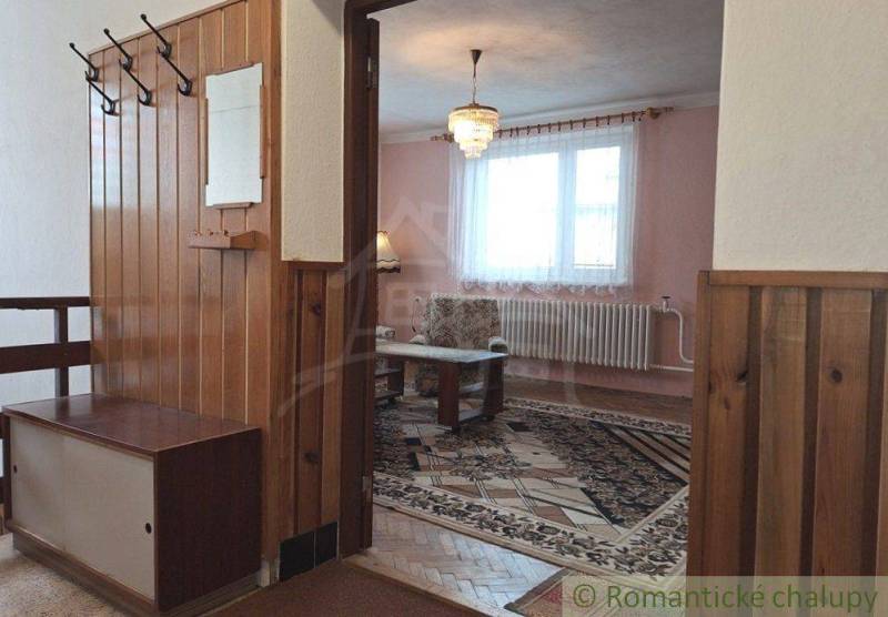 An elongated interior of a family house with wooden paneling and carpets.
