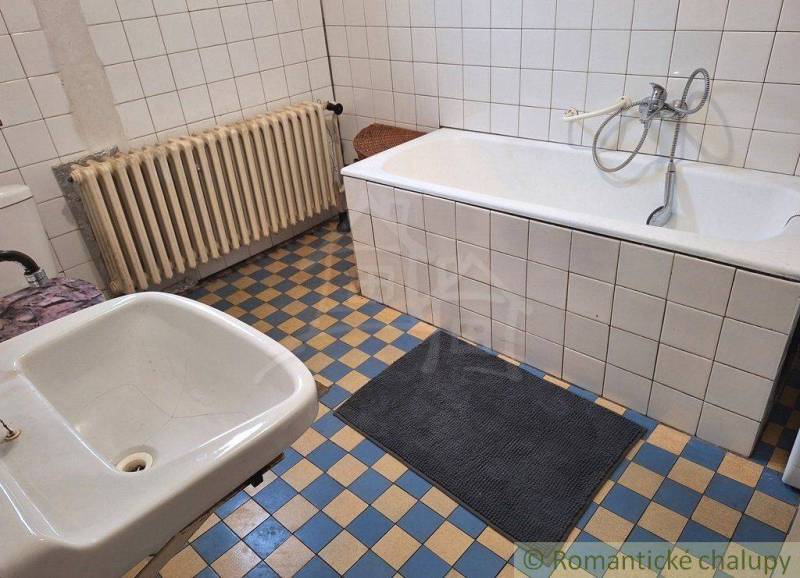 A bathroom with an old bathtub, sink, radiator, tiles, family house, bathrooms.