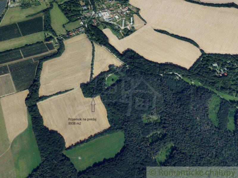 An aerial view shows a plot of land for sale amidst fields and forests for recreational purposes.