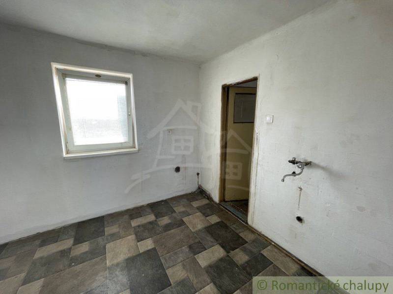 A room with tiles, a sink, a simple window. The family house needs interior renovation.