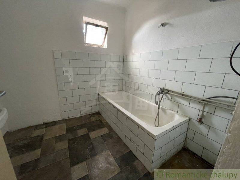 A bathroom with a bathtub and older tiles, a base for renovation in a family house.