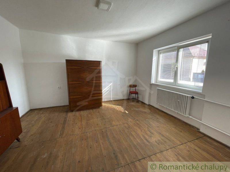 A bright room with a wooden floor, a window, furniture, and a piece of a radiator, family house.