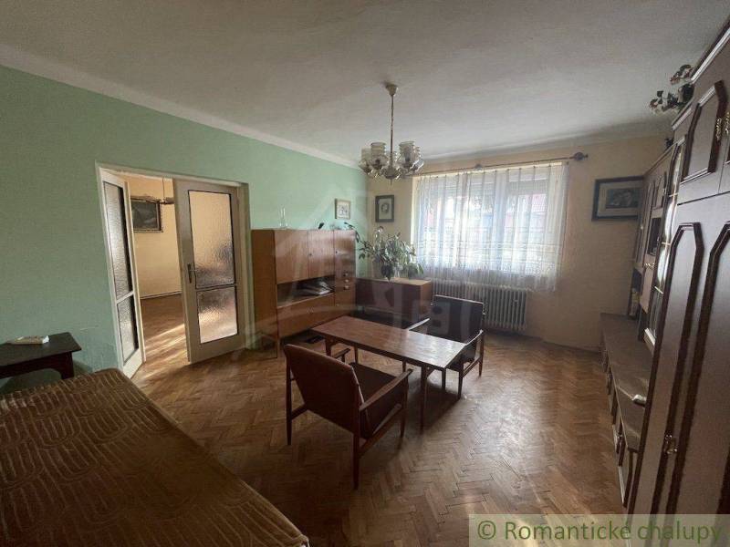 A living room in a family house with older furniture and wooden flooring.