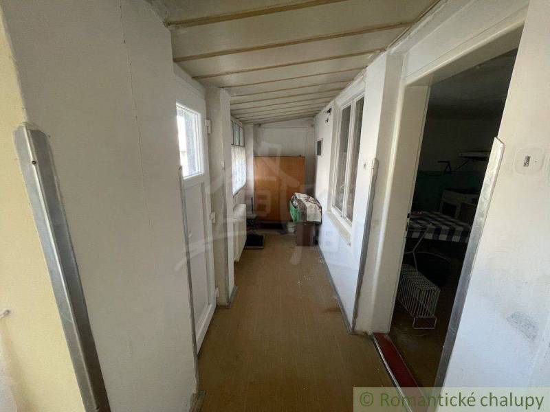 A narrow hallway in a family house, white wooden wall and furniture.