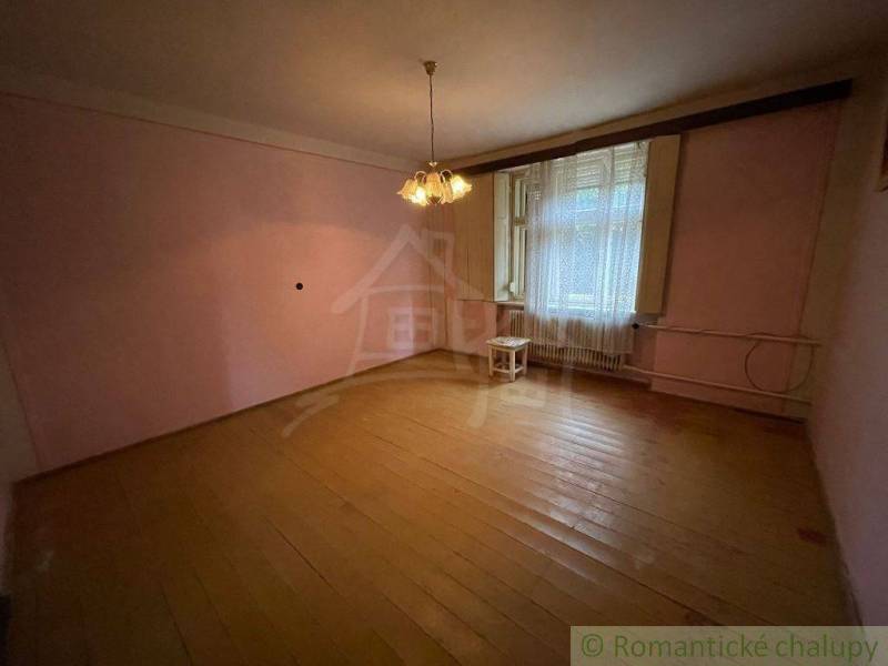 A spacious living room in a family house with light wooden floors and a chandelier.