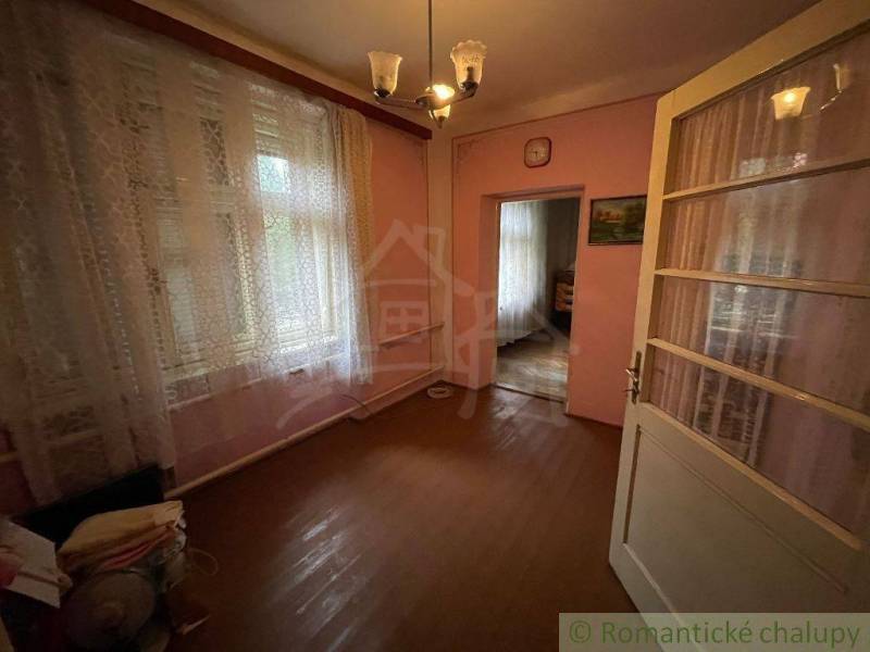 A room with a wooden floor, curtains, paintings, and light in a family house.