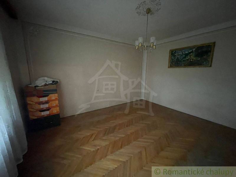 A dark room in a family house with parquet flooring, a painting, and cardboard boxes in the corner.