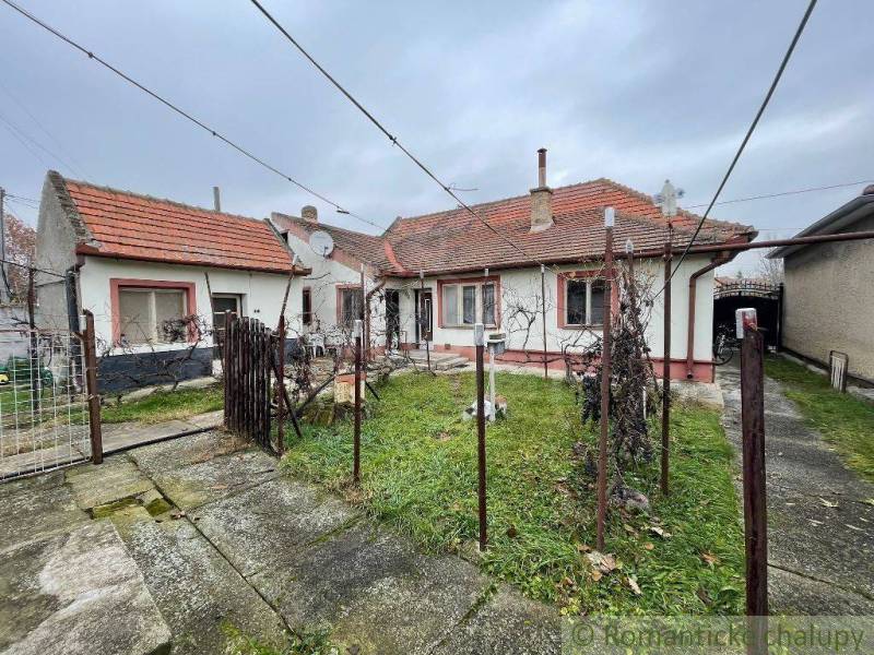 A family house with a red roof, a yard with a lawn, and a concrete walkway.