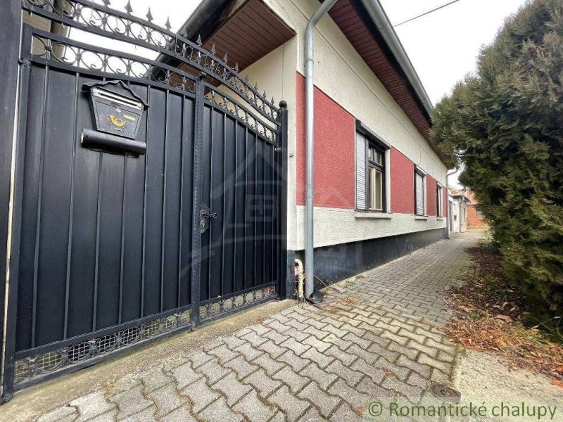 A family house with an iron gate and a small gate stands out with an entrance to a paved walkway.